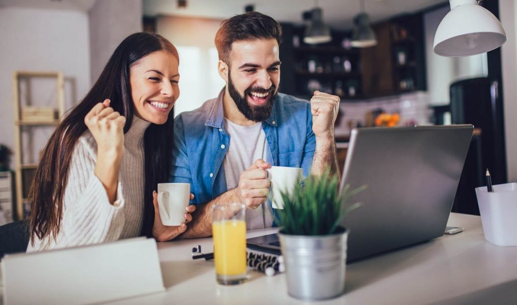 Young couple comparing Questrade and Wealthsimple on laptop