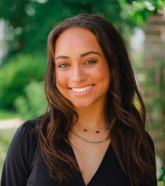 Professional photo of Maya Reynolds standing in front of greenery