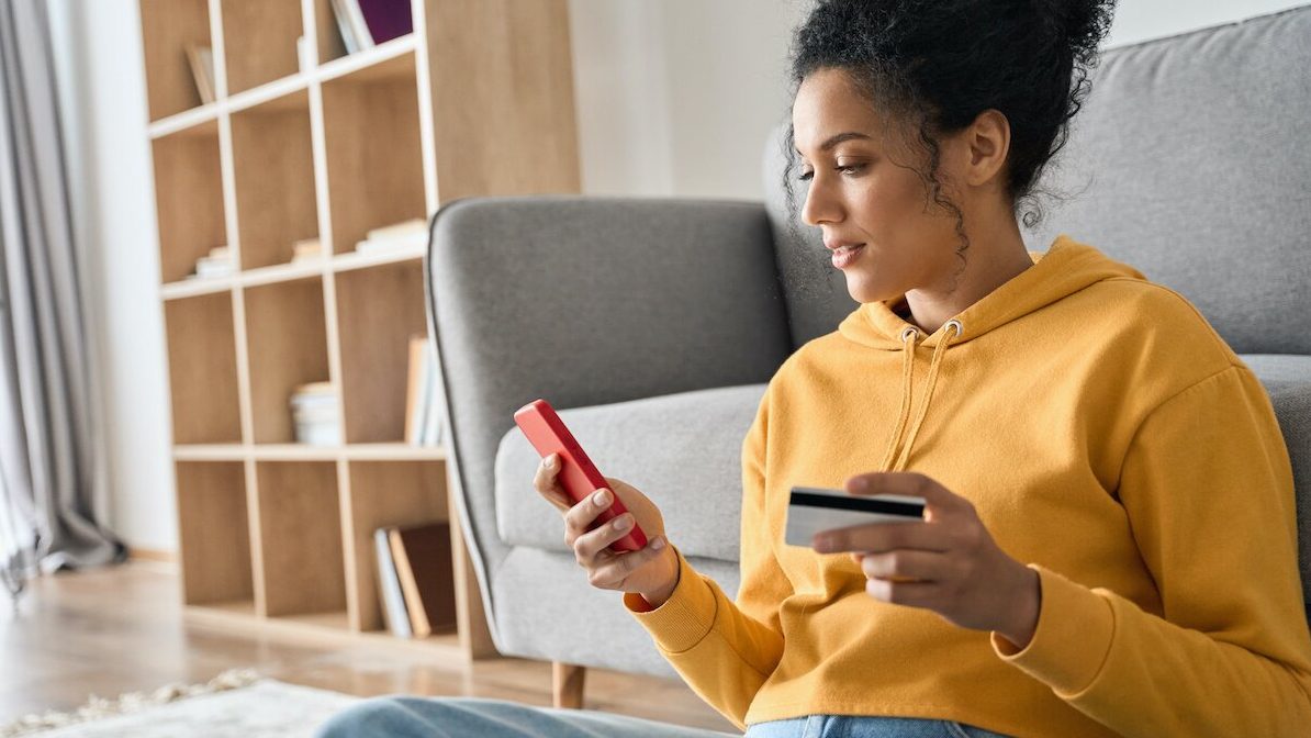 Image of young woman increasing credit score on mobile device